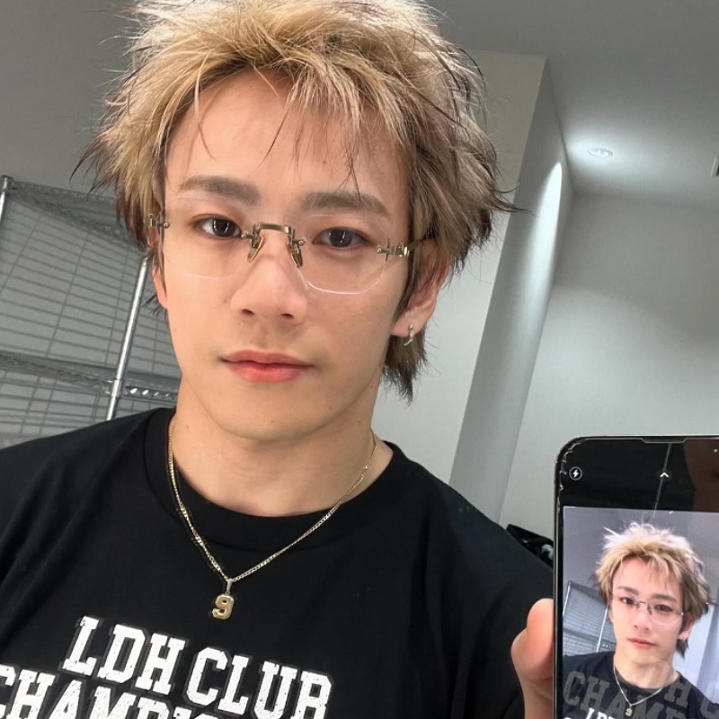 黒いシャツを着てスマホ画面を見せる浦川翔平の画像