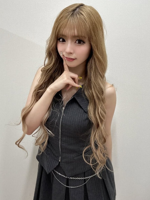 ゆいちゃみ(ゆい小池)がグレーの服を着て右手人差し指で頬を触る画像