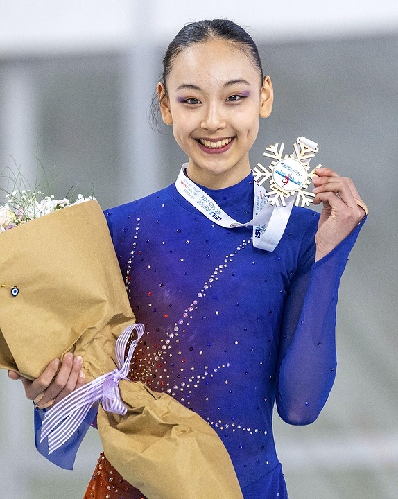 青いコスチューム姿で雪の結晶のメダルと花束をもつ岡万佑子の画像