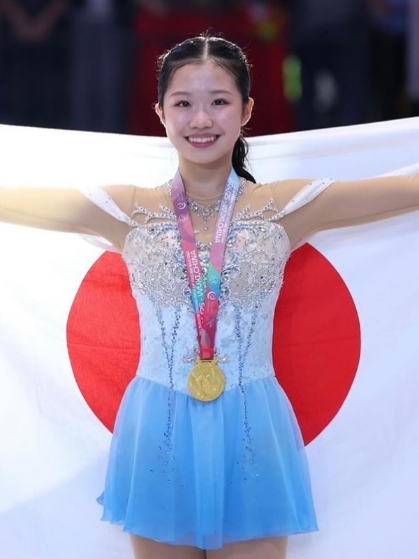 金メダルを首にかけ日の丸を背に掲げる中井亜美選手の画像
