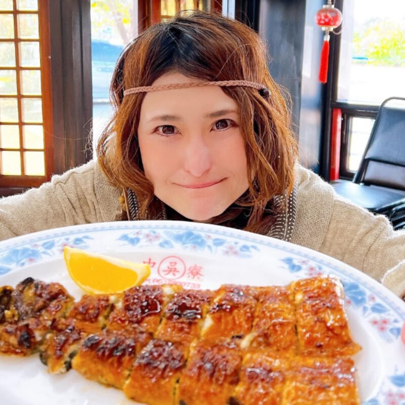 ウナギのかば焼きを持つアンジェラ佐藤の画像