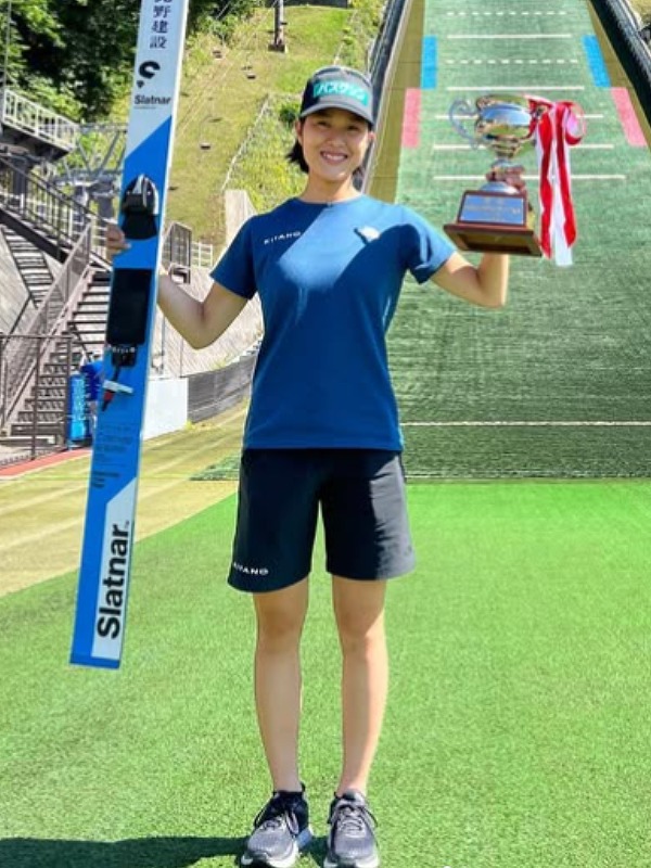 丸山希がサマージャンプでスキーとトロフィーを掲げる画像
