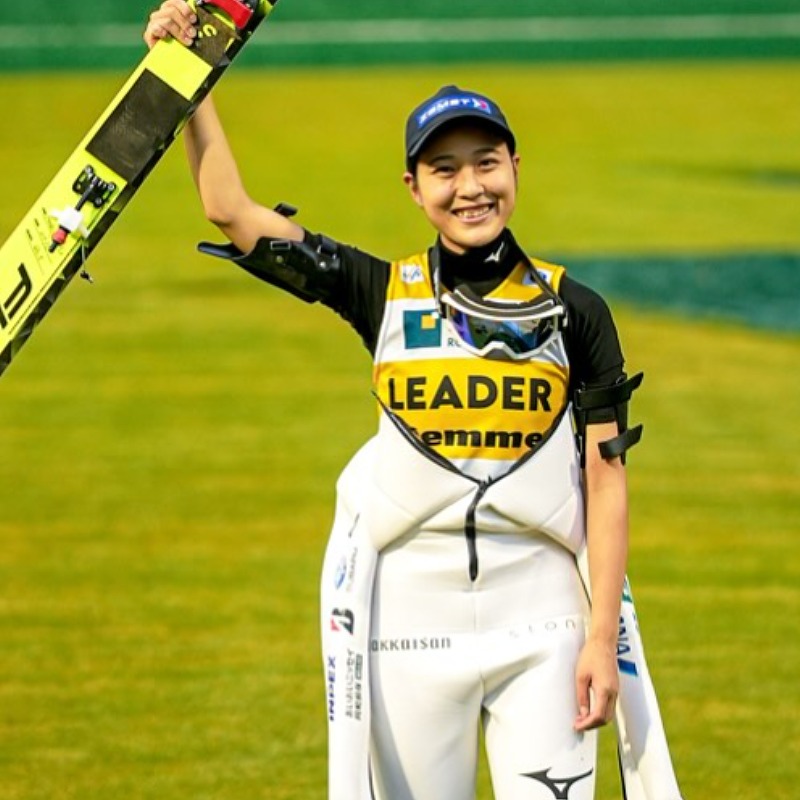 丸山希がジャンプ後、ウエアを脱ぎスキーを掲げる画像