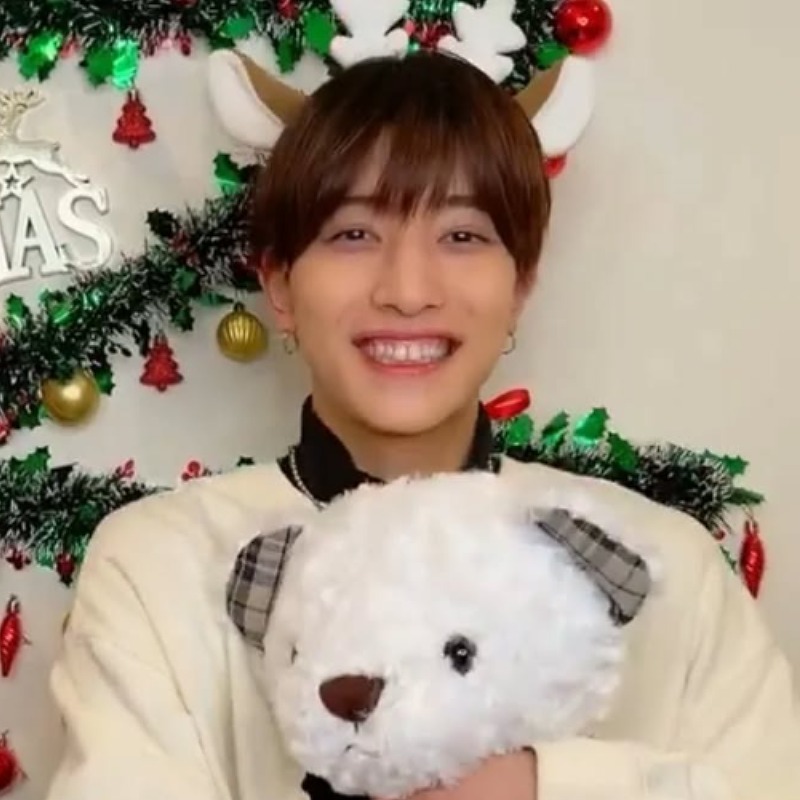 中村嶺亜がクリスマスの飾りの前で白い熊のぬいぐるみを抱いている画像