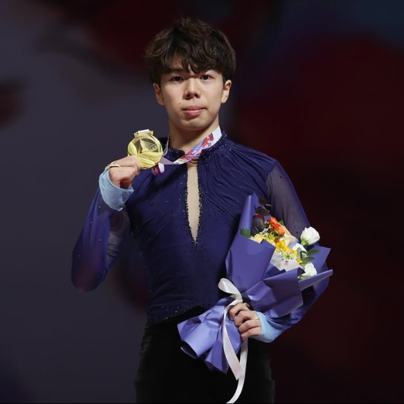 金メダルを首にかけ花束を持つ佐藤駿の画像