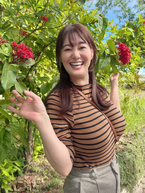 竹中知華が赤い花の近くに立つ画像