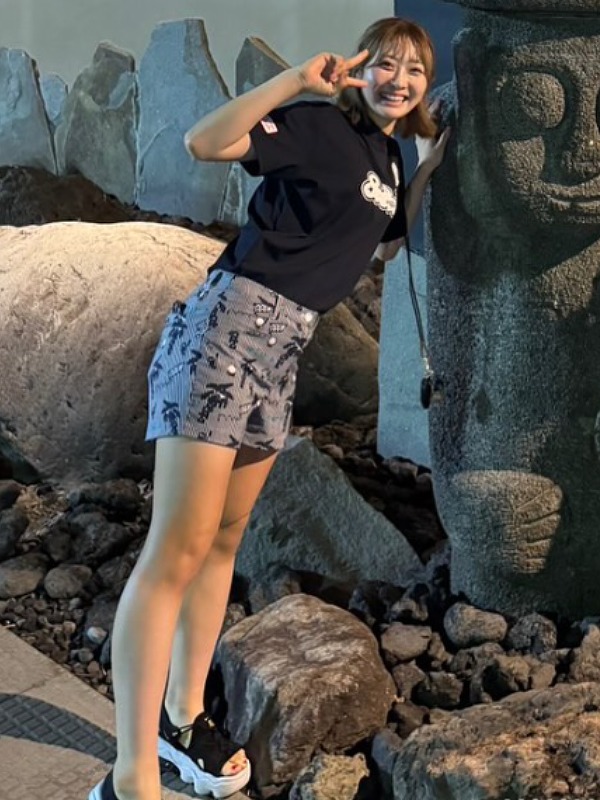 都玲華が石像の横でピースサインをする画像