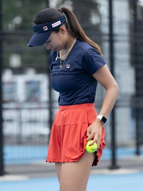 園田彩乃が紺とオレンジのウエアを着てコートに立つ画像