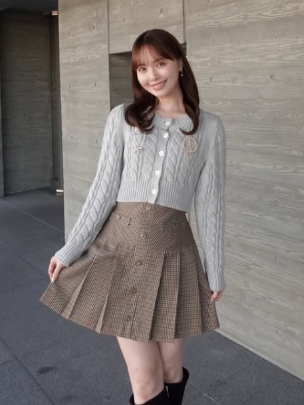 山根千佳がグレーのニットとチェック柄の茶色いスカートを身に着けている画像