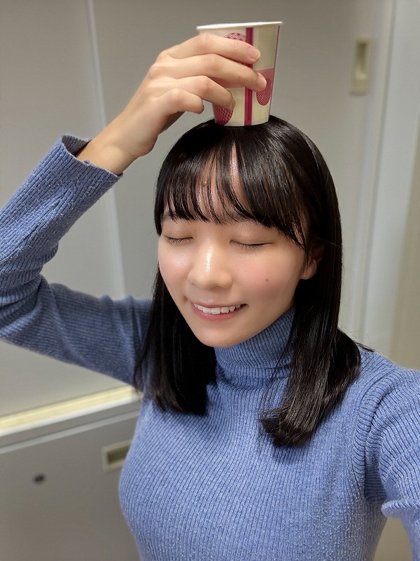 椿野ゆうこが空色のニットを着て頭に紙コップを乗せている画像