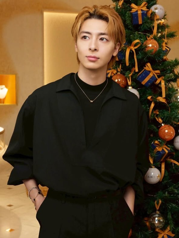 高杉真宙 が黒い服を着てクリスマスツリーの前に立つ画像