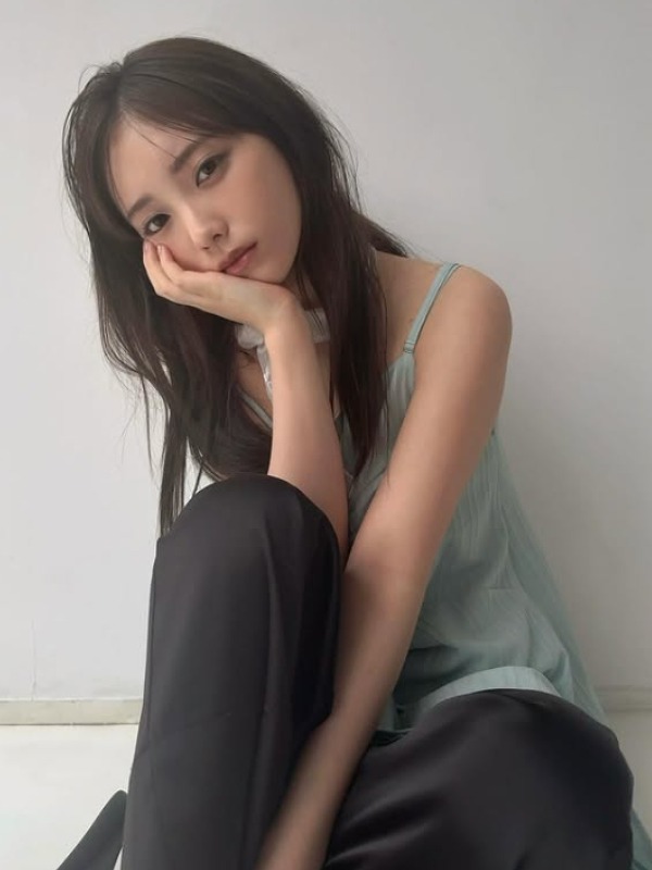 与田祐希が片膝を立てて座り頬杖をつく画像