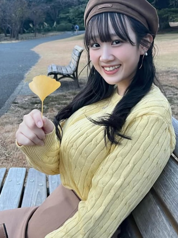 奥村梨穂が黄色いセーターを着て銀杏の落ち葉を持つ画像