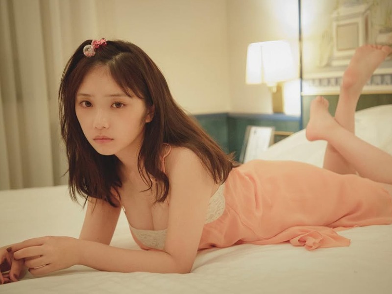 与田祐希がピンク色の服を着て寝そべる画像