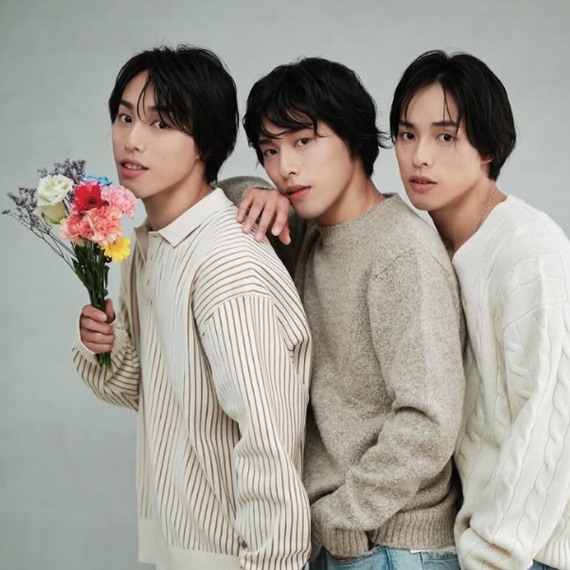 佐藤三兄弟が茶色系の服を着ている画像 兄が花束を持つ