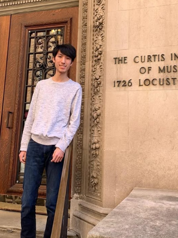 エリック・ルーが長袖Tシャツにジーンズ姿で扉の前に立つ画像