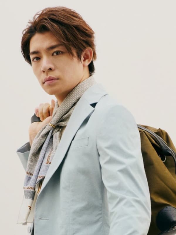 岸優太が空色のジャケットを着てバッグを背負う画像