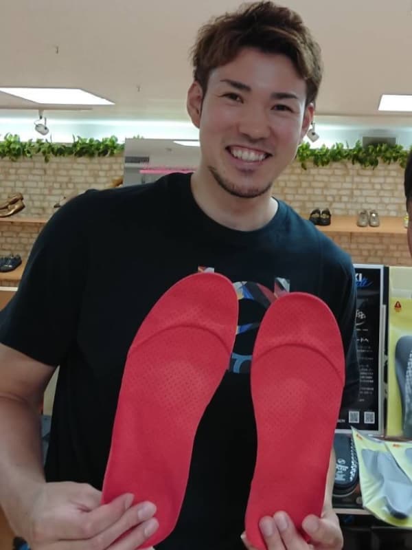 金丸晃輔が赤く大きなインソールを両手に持つ画像