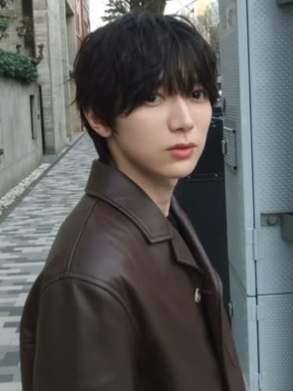 七五三掛龍也が茶色いレバーのアウターを着て歩道に立つ画像