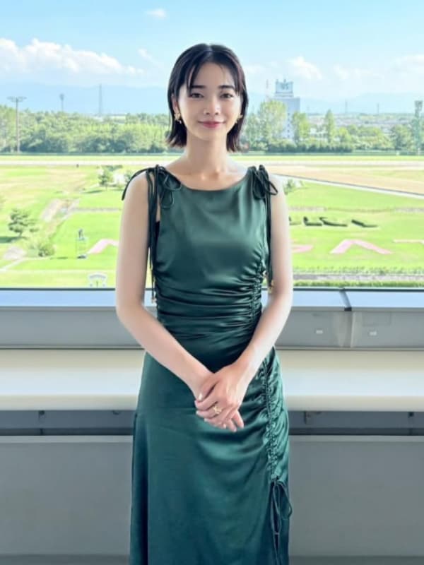 見上愛が緑色のドレスを着て競馬場に立つ画像