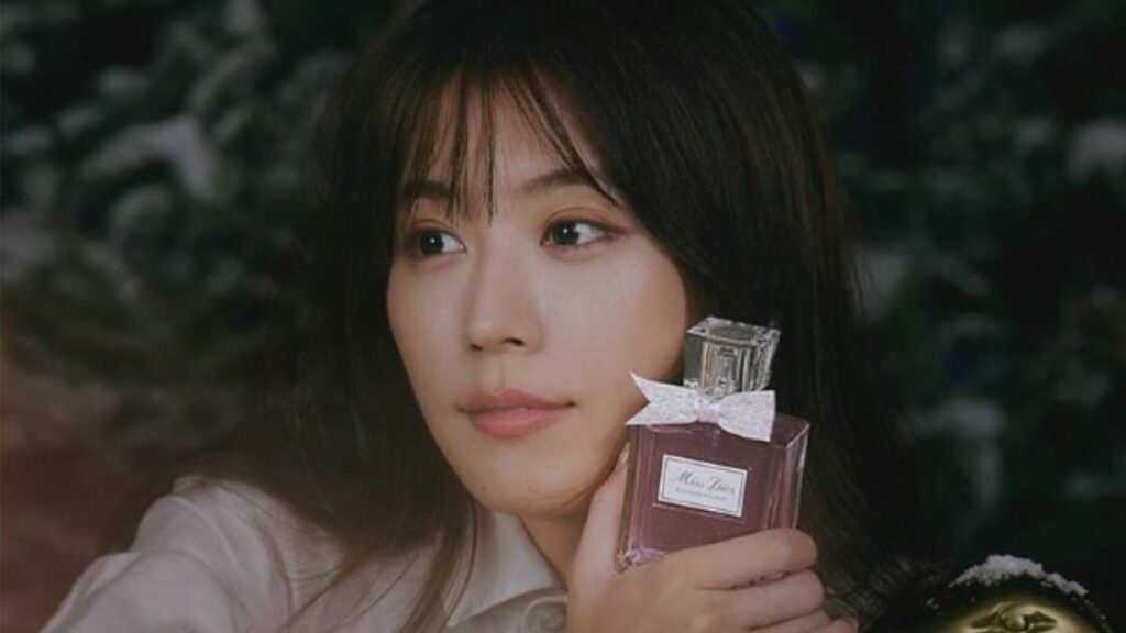 有村架純がピンク色の香水瓶を手に持ち、柔らかな光の中で物憂げに横を見つめるクローズアップ。透け感のある前髪とナチュラルなメイクが、彼女の持つ透明感を強調している。