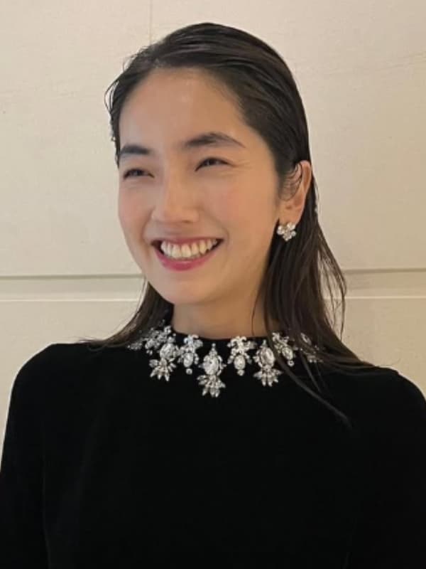 仁村紗和が黒い服を着て微笑む画像