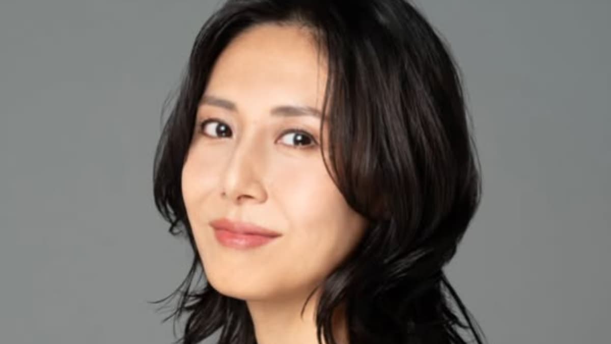 グレーの背景をバックに微笑む松嶋菜々子のアップ。黒髪のウェーブヘアが印象的な落ち着いた雰囲気のポートレート。