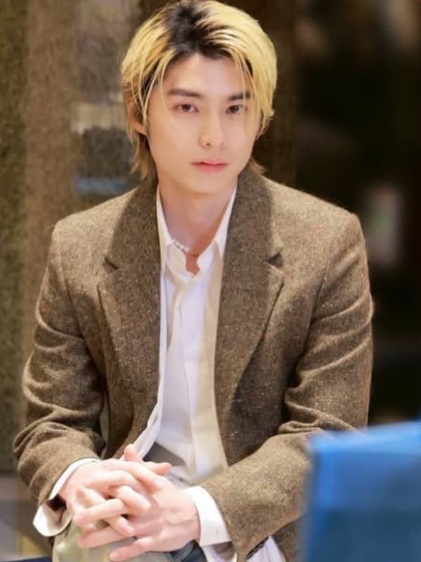 本田響矢が茶色のジャケットを着て両手を組み座る画像