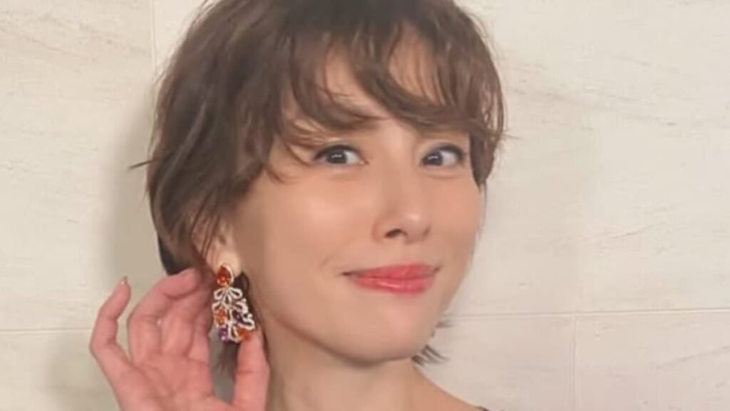 ショートボブのウェーブヘアに、オレンジとパープルの宝石が輝く大ぶりのイヤリングを合わせた米倉涼子のアップ写真。