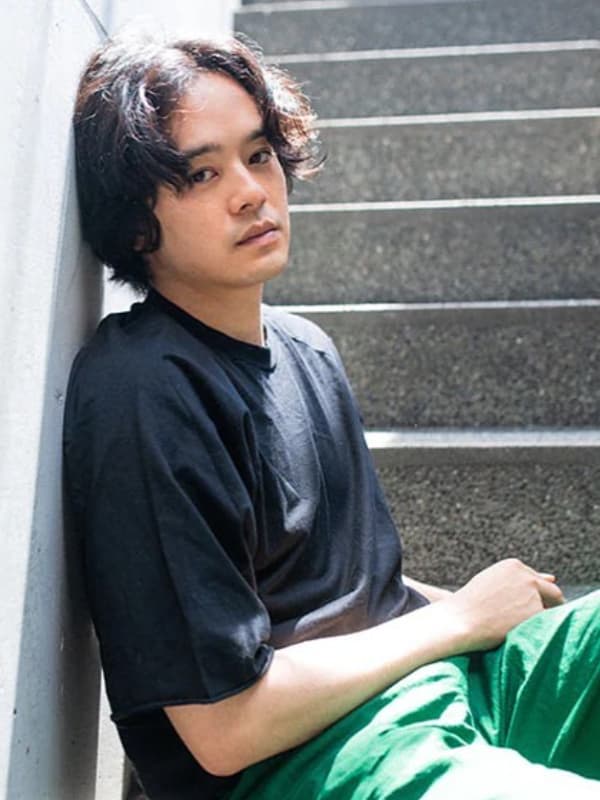 池松壮亮が屋外の階段に座り壁に寄り掛かる画像