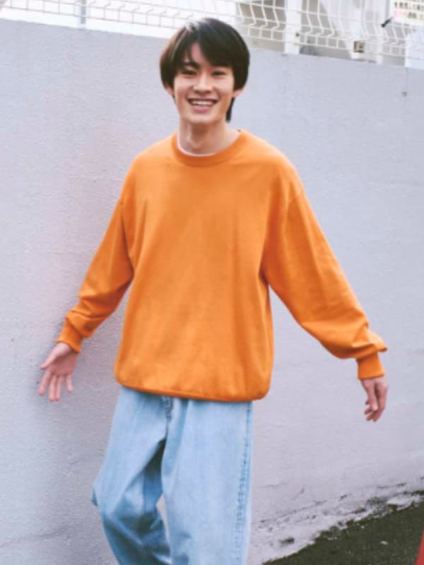 山時聡真がオレンジ色の服を着て白い壁際を歩く画像