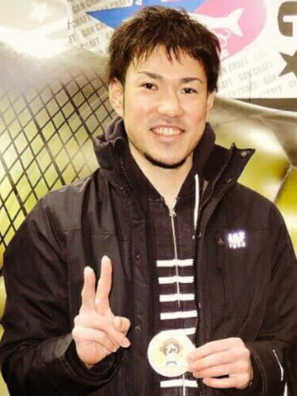 金丸晃輔が黒い服を着てピースサインをする画像