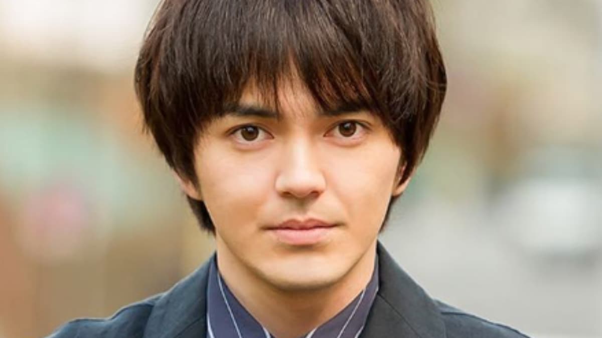 正面を向いてカメラを見つめる俳優の林遣都。黒いジャケットとストライプのシャツを着用している。