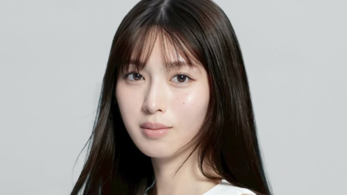 正面を向き、ニュートラルな表情でカメラを見つめる白石聖のポートレート。白いトップスを着用し、明るいグレーの背景。