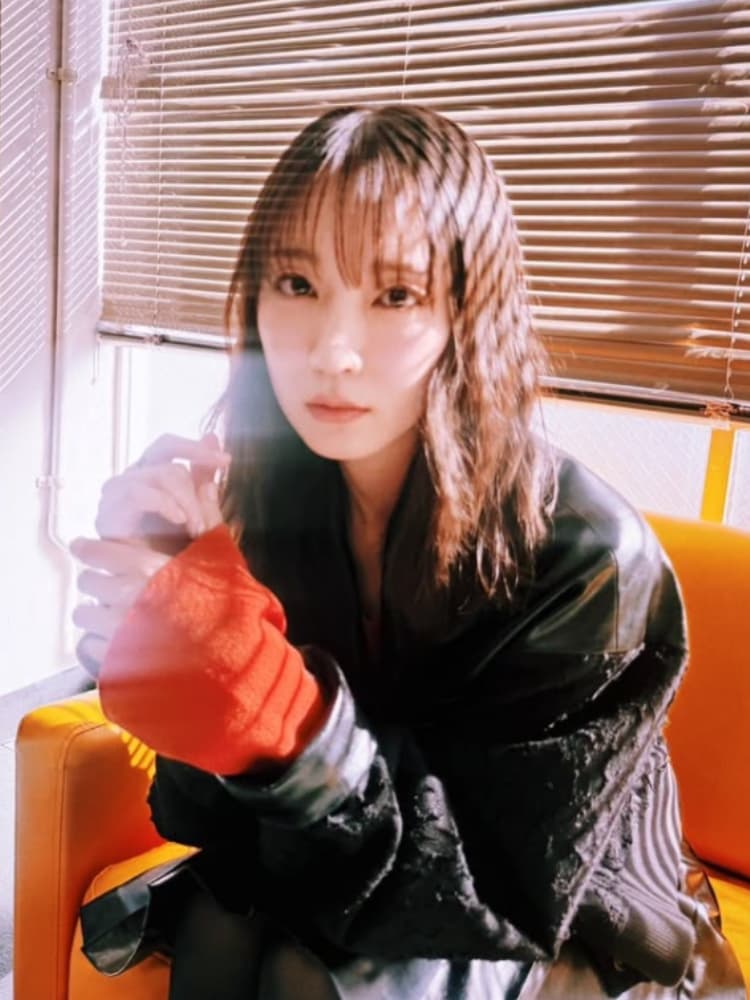 ブラインドから差し込む光の中で、レザージャケットと赤いスリーブを合わせた吉岡里帆。スタイリッシュな一枚。