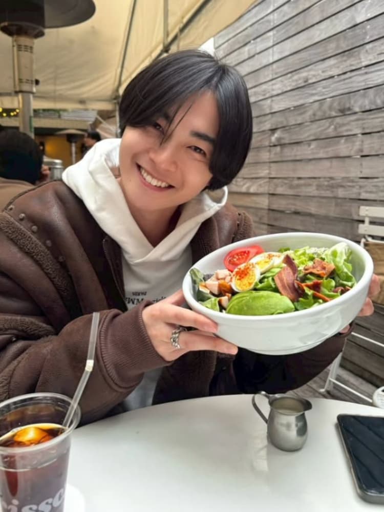 カフェでサラダボウルを持って笑顔を見せる俳優の結木滉星氏。カジュアルなジャケットとパーカー姿。