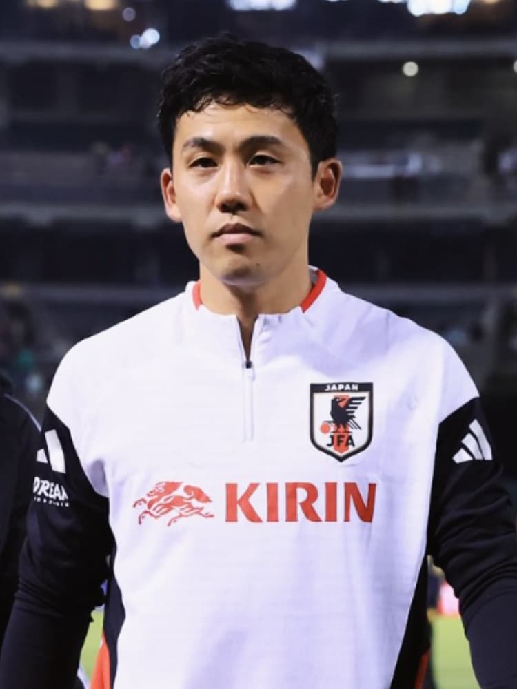 白と黒のツートンカラーの日本代表トレーニングウェアを着用し、夜のスタジアムを背景に、引き締まった表情で正面を見据える遠藤航選手。