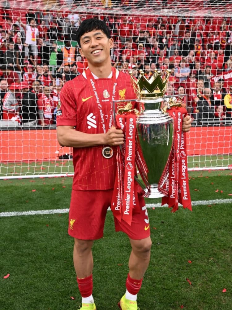 リヴァプールFCのユニフォーム姿で、優勝メダルを首にかけ、笑顔でカラバオ・カップ(リーグカップ)のトロフィーを掲げる遠藤航選手。