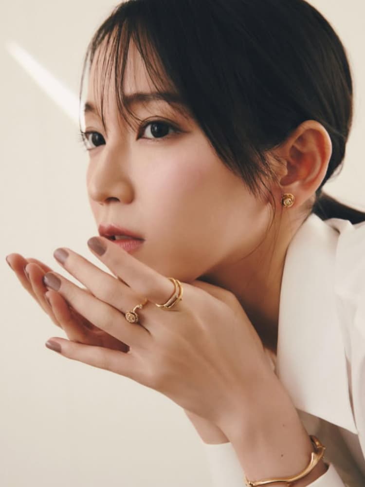 白いシャツを着て、両手を重ねて指輪とブレスレットを強調する吉岡里帆。自然な表情。