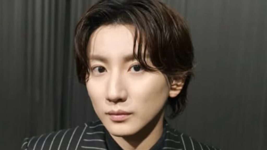 グレーに白いストライプのスーツと黒いインナーを着用した京本大我のクローズアップポートレート。グレーのカーテンを背景に、正面を見つめている。