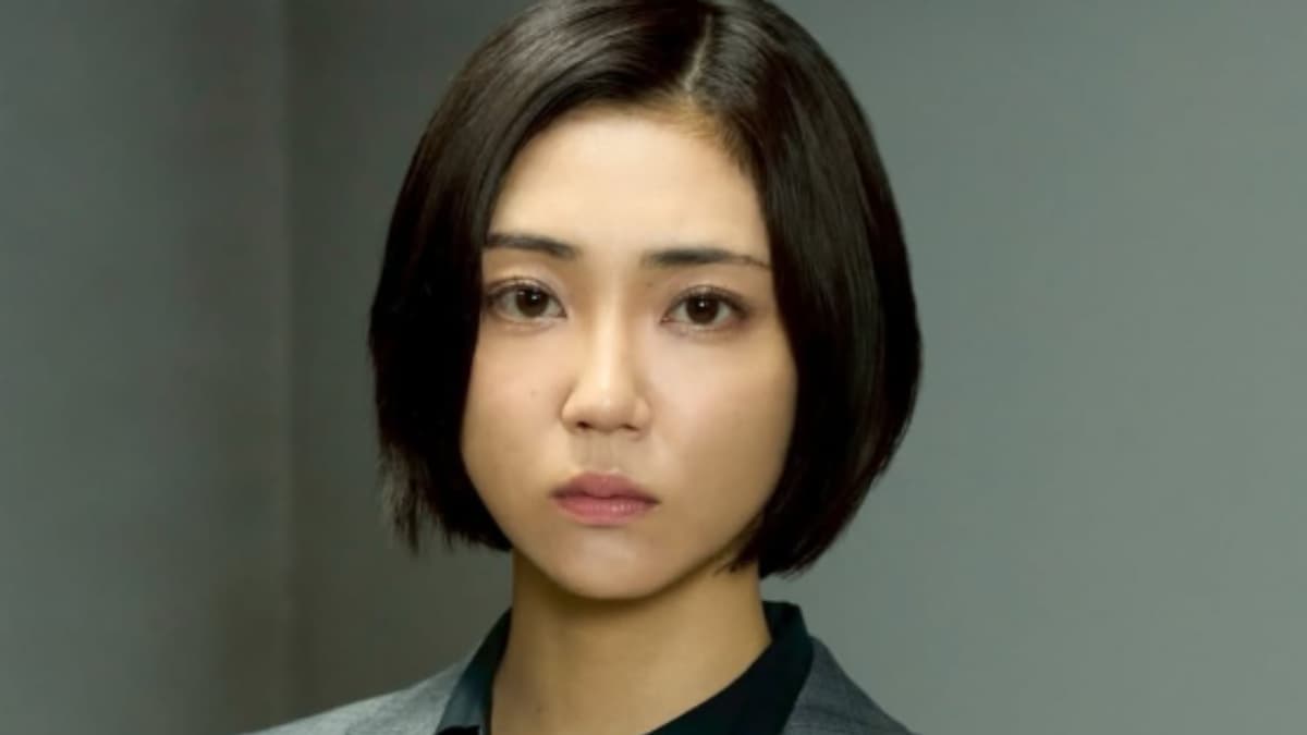 暗いショートボブヘアで真剣な表情をした山谷花純の正面アップ写真。グレーのジャケットと黒いトップを着用している。背景はぼやけたグレー。