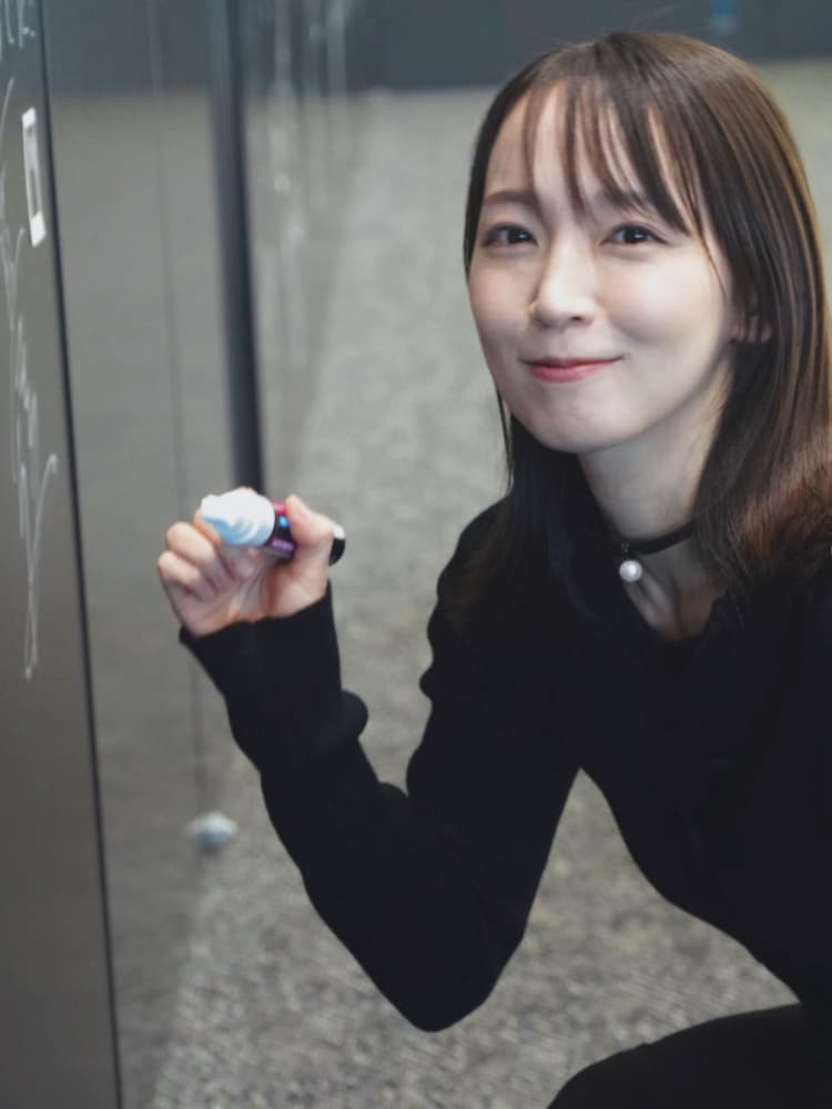 黒いチョーカーをつけ、ペンを手に持ちながらカメラに向かって微笑む吉岡里帆。