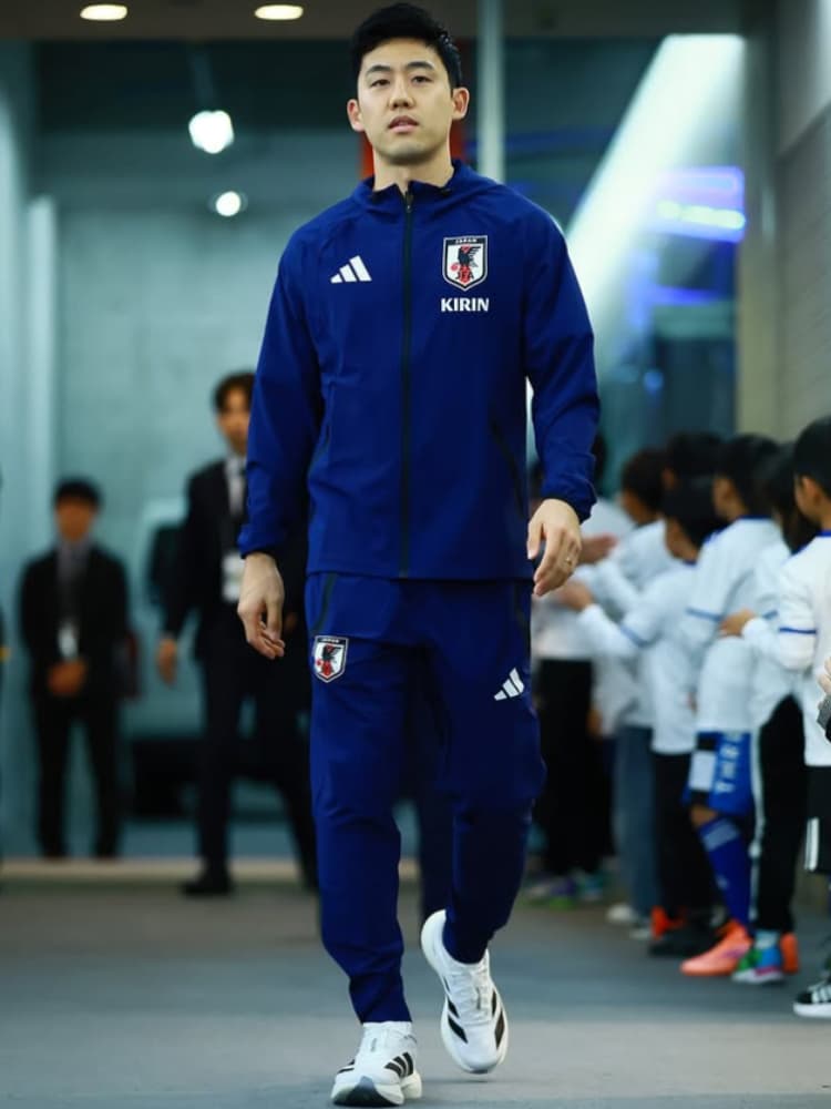 日本代表の青いアディダス製トレーニングウェア(KIRINロゴ入り)を着用し、スタジアムの通路をまっすぐ前を見つめながら歩く遠藤航選手。