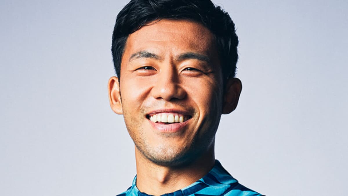 青い幾何学模様のプーマ製トレーニングウェアを着用し、正面を向いて満面の笑みを浮かべる遠藤航選手のクローズアップ写真。