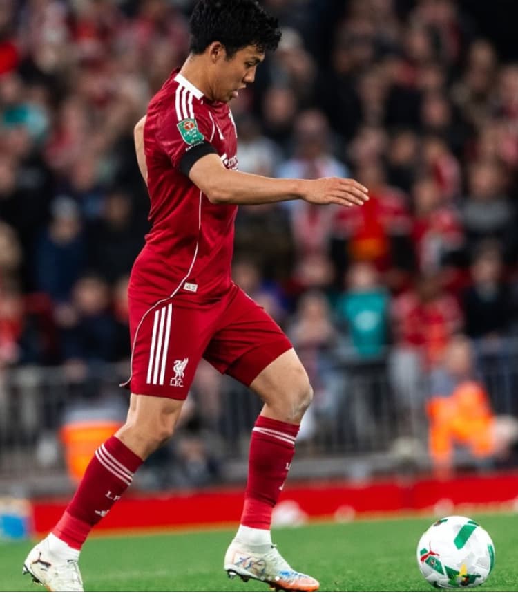 リヴァプールFCの赤いホームユニフォームを着用し、試合中にサイドからピッチ中央へ向かってボールを運ぶ遠藤航選手の横顔。