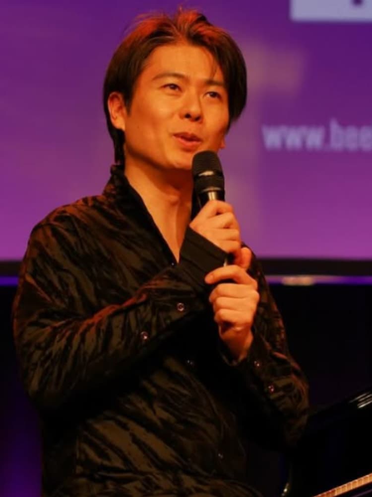 ステージ上でマイクを持ち、トークセッションで話す福間洸太朗。