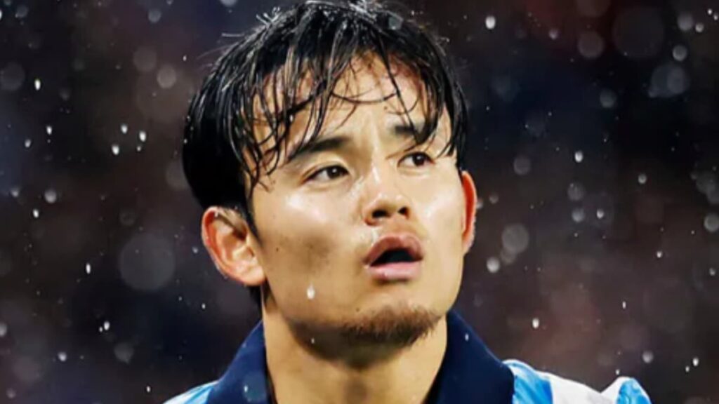 雨の中、レアル・ソシエダの青と白のストライプユニフォームを着用し、口を開けて上を見上げる久保建英のクローズアップ。