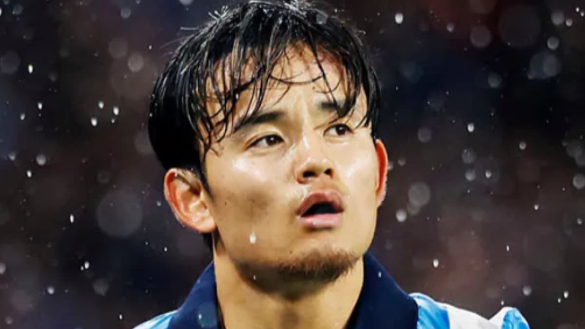 雨の中、レアル・ソシエダの青と白のストライプユニフォームを着用し、口を開けて上を見上げる久保建英のクローズアップ。