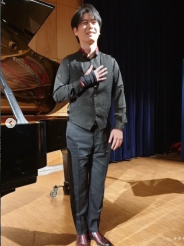 コンサートのステージで、グランドピアノの横に立ちお辞儀をする福間洸太朗。