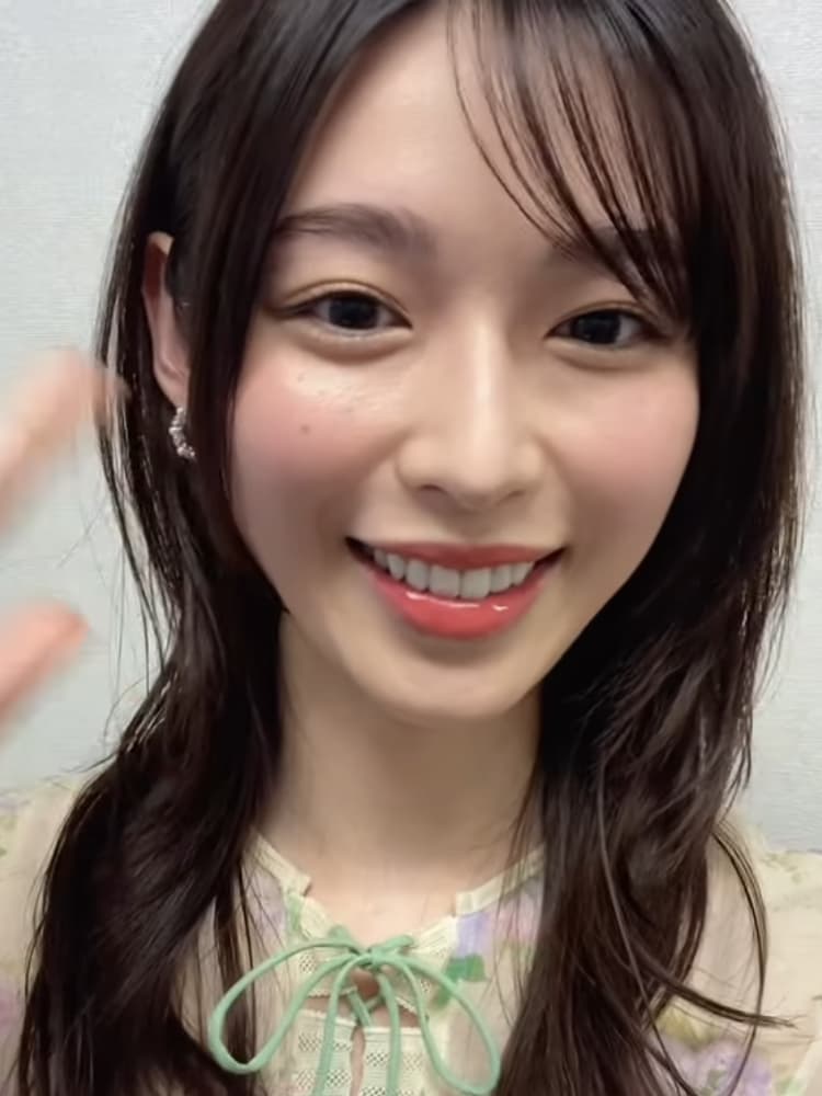 カメラに向かって満面の笑みで手を振る、花柄トップスを着た白石聖のアップ。